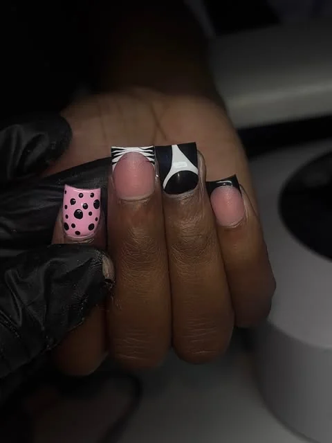 Pink and black French tip nails with polka dots and white line details.