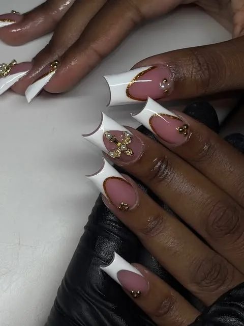 White French tip nails with gold floral accents and delicate rhinestones.