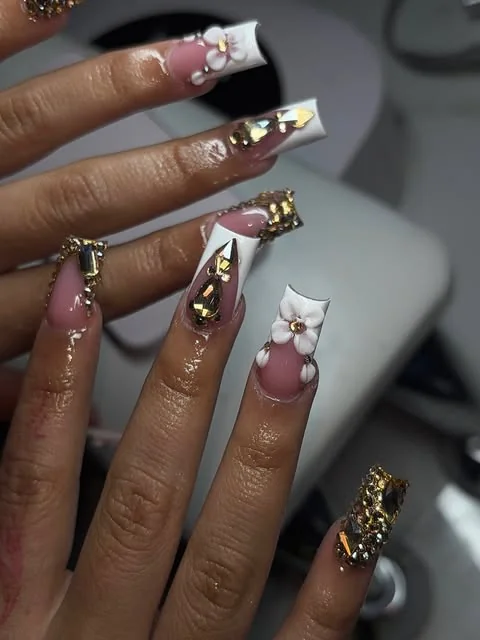 Long pink and white nails with sculpted flowers, bows and gold embellishments.